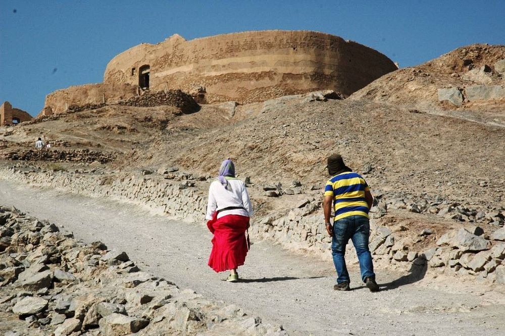люди идут к древней башне в пустыне