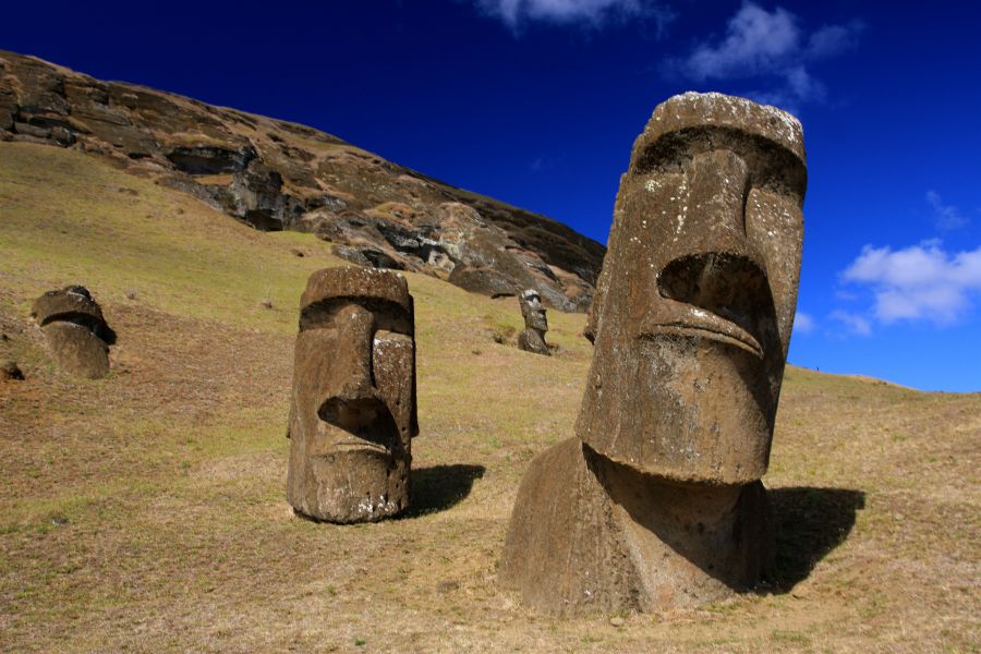 статуи острова Пасхи у горы на фоне голубого неба