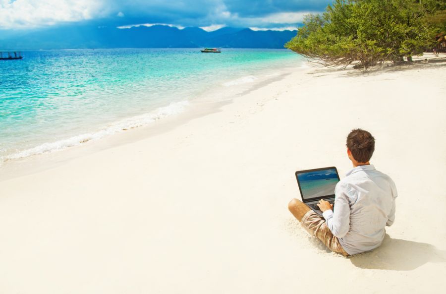 мужчина с компьютером сидит на пляже, жизнь на Бали