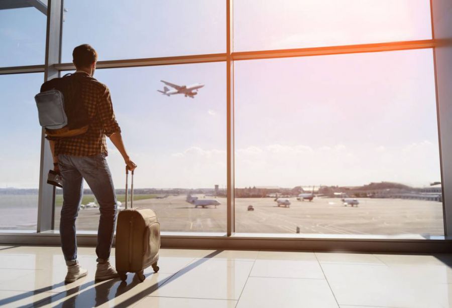 парень в аэропорту, смотрит на самолет, парень с чемоданом, как купить дешевые авиабилеты
