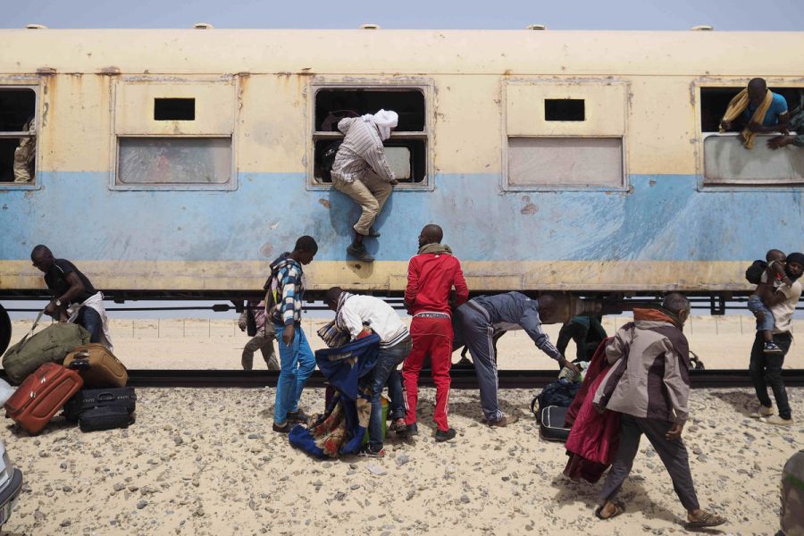 поезд жизни в мавритании, люди возле рельс, поезд в пустыне, люди запрыгивают в поезд